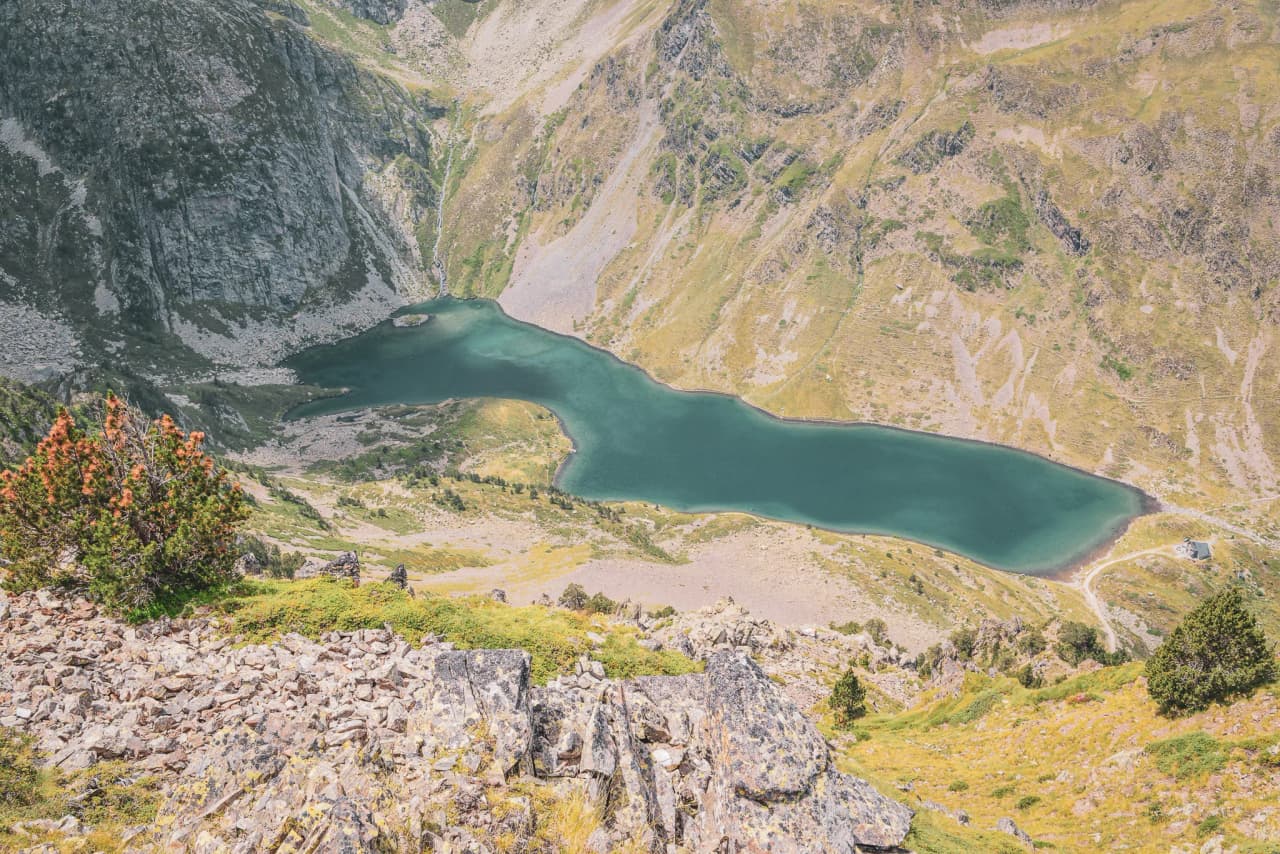 A turquoise lake surrounded by green mountains and rocky outcrops, an invitation to adventure.
