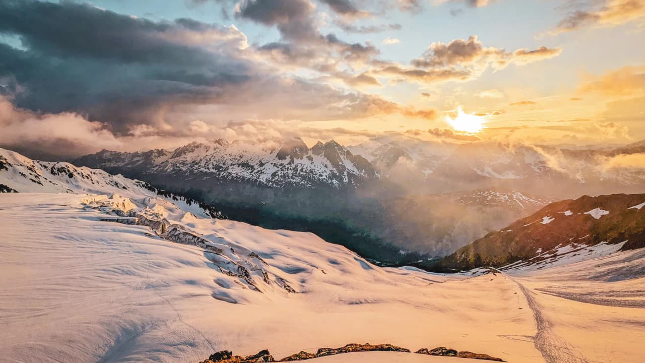 Paysage alpin époustouflant au coucher du soleil, glaciers scintillants et sommets majestueux.
