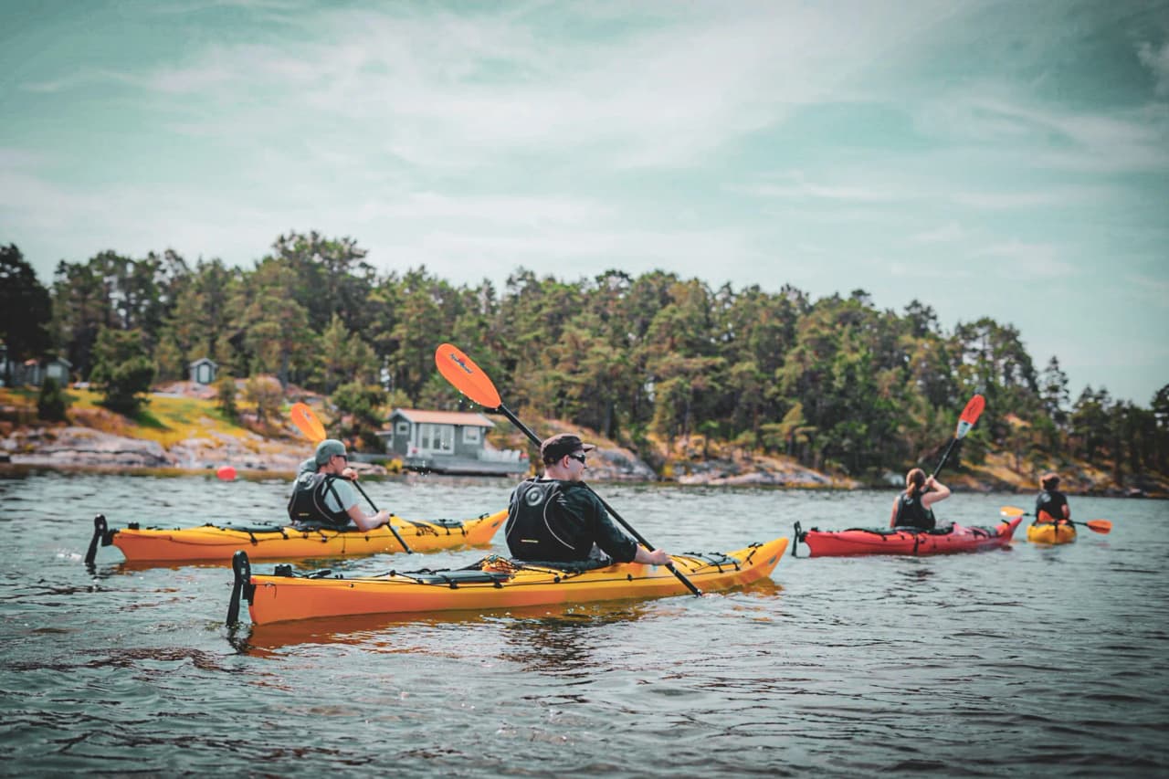 Four kayakers navigate the peaceful waters of the Stockholm archipelago, surrounded by nature.