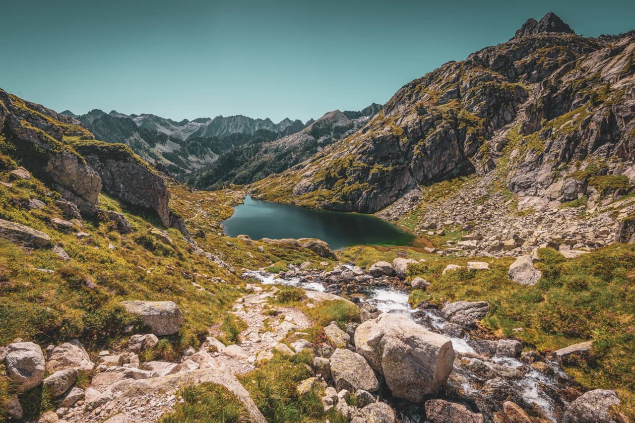 Magnificent Pyrenean scenery, with a high-altitude lake surrounded by lush green mountains.