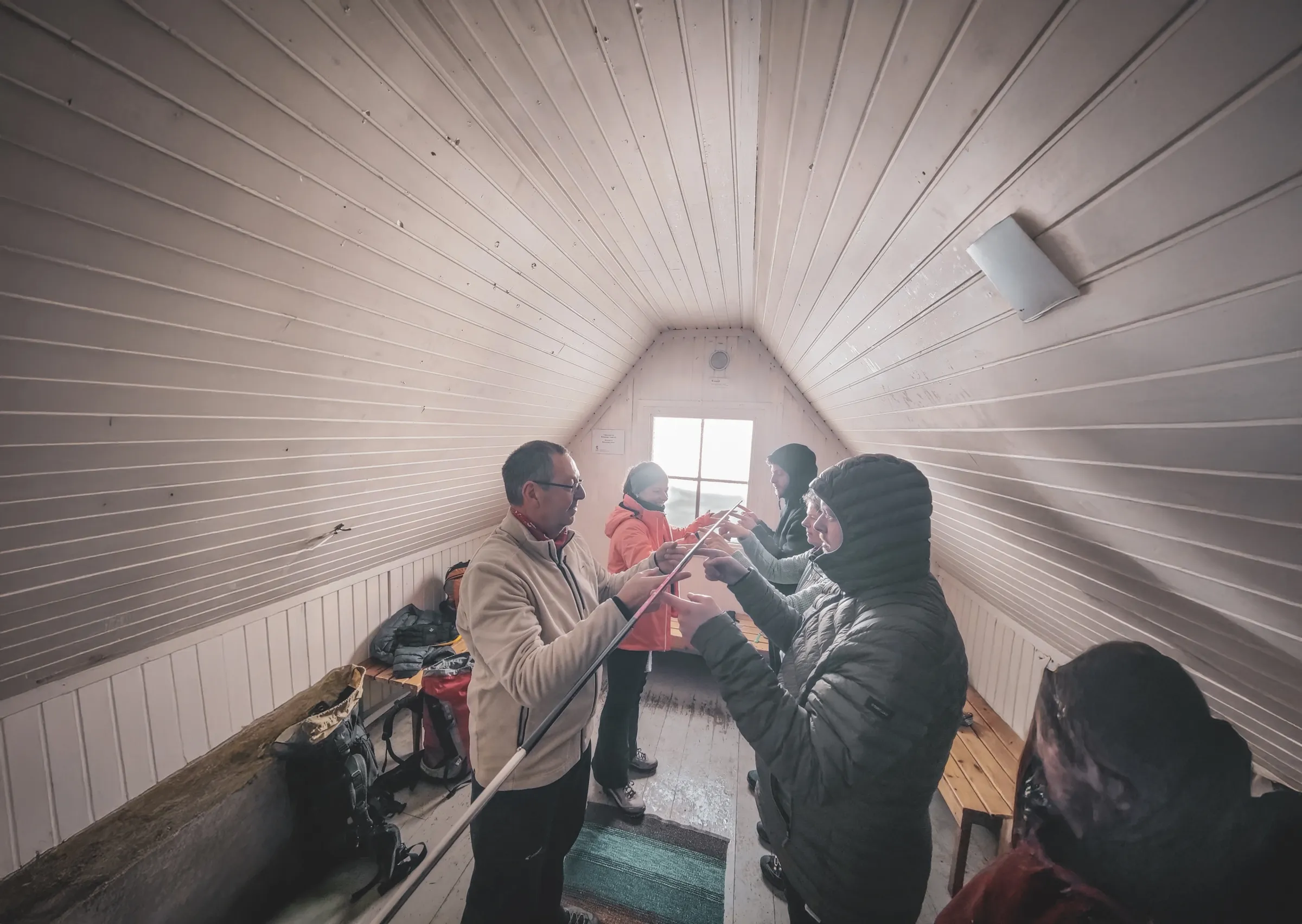 Groupe d'expédition en Laponie suédoise, échange de matériel dans un refuge chaleureux.