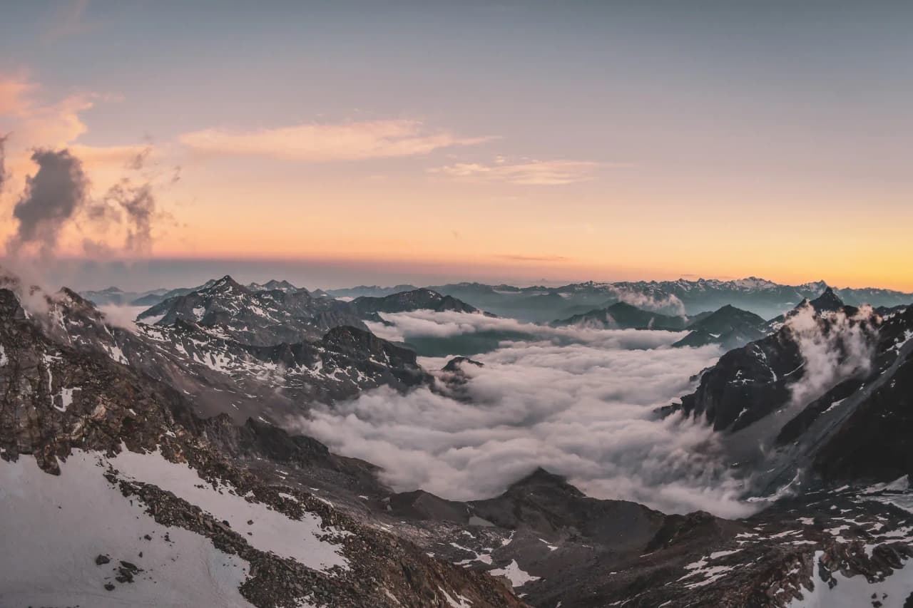 Lever de soleil majestueux sur les sommets des Alpes, entourés de nuages. Un rêve d'évasion.
