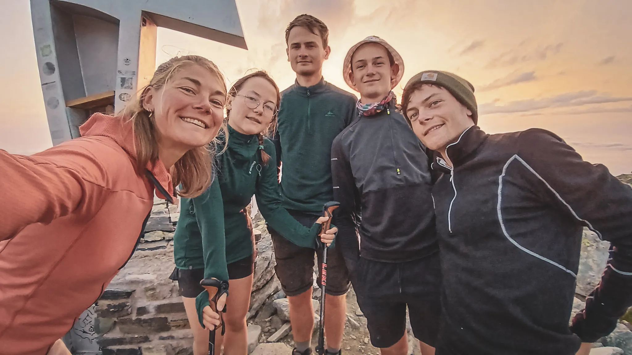Een groep lachende wandelaars op de top, klaar om het alpenlandschap van de Mont Viso te verkennen.