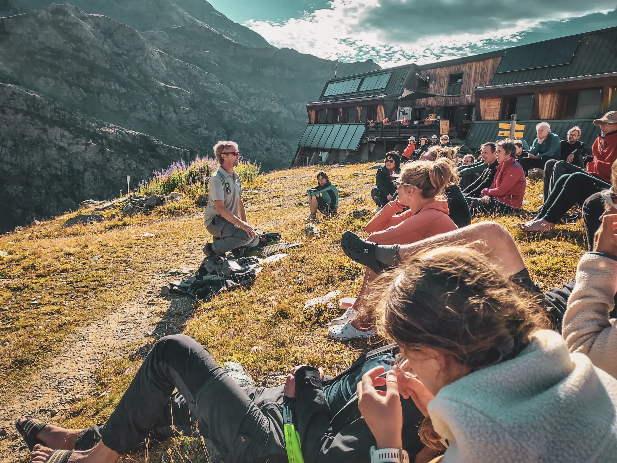 Groupe rassemblé en pleine nature, écoutant un guide face aux montagnes majestueuses du Mont Viso.