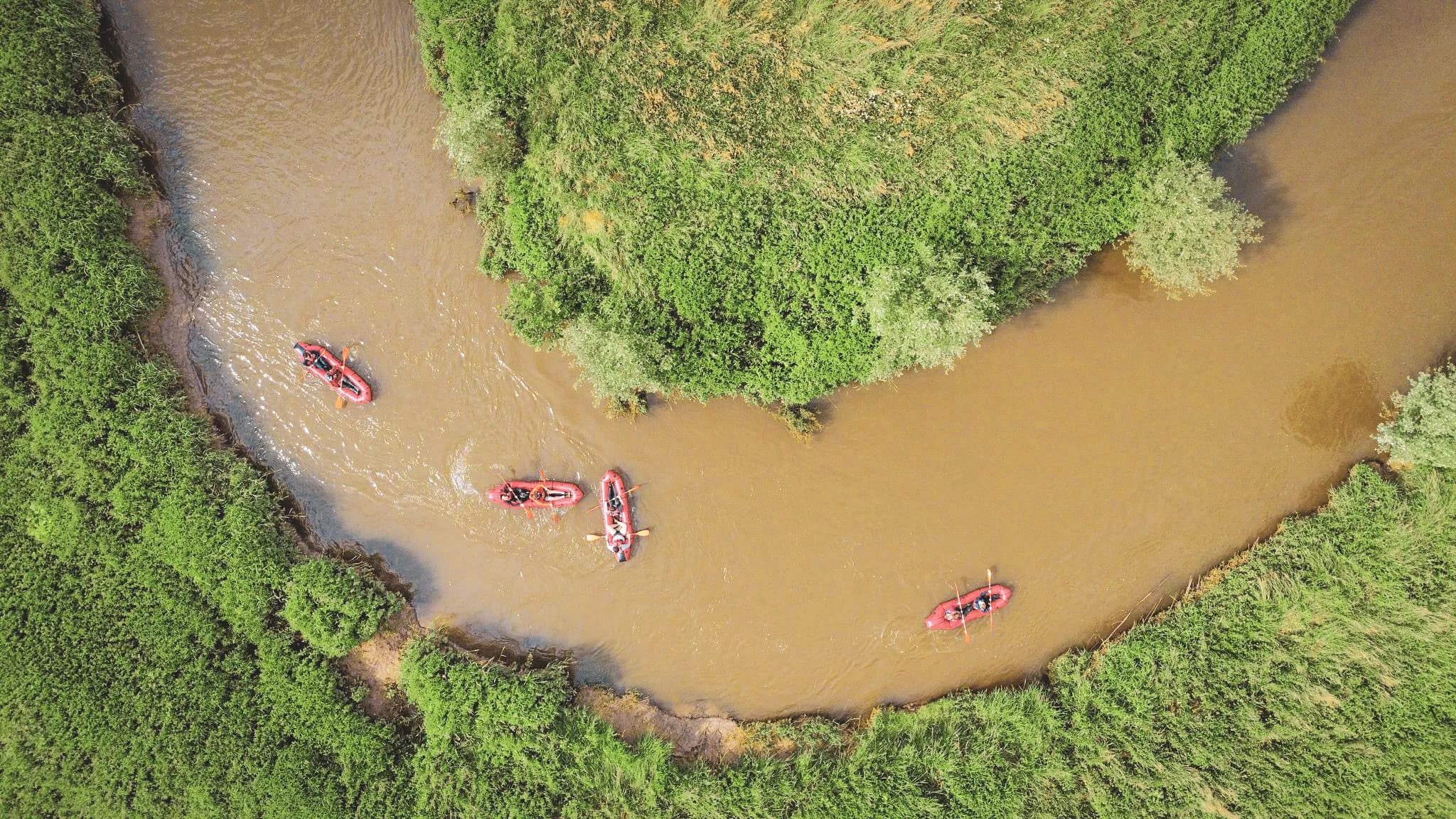 Packraft on a winding river surrounded by lush greenery in Belgium.
