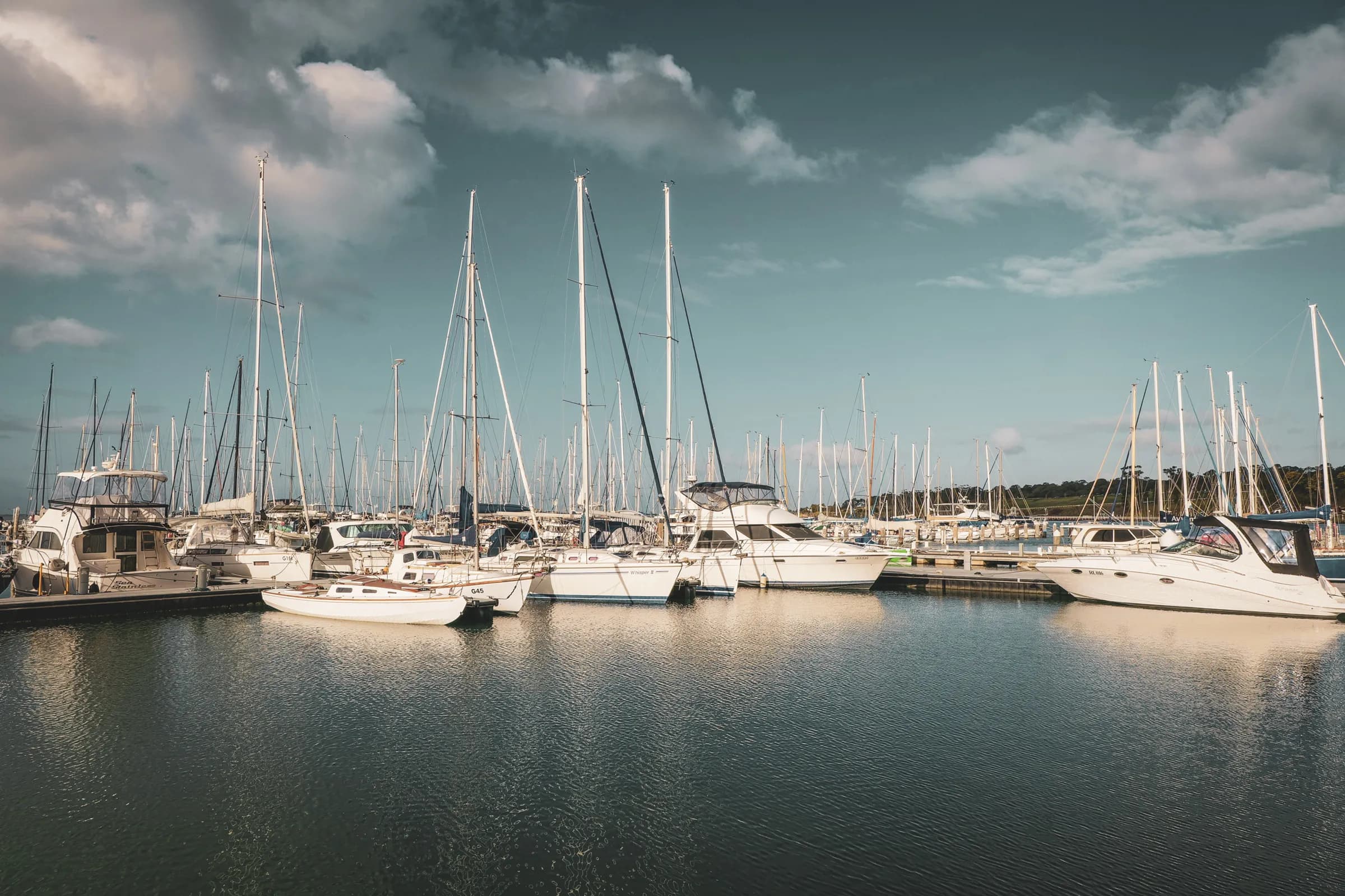 Port tranquille en Corse, voiliers amarrés sous un ciel bleu. Invitation à l’évasion maritime.