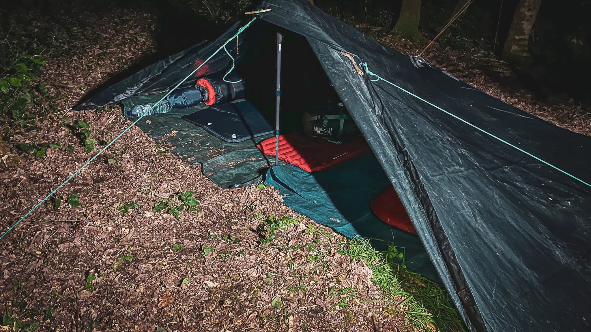 Tente de survie dans les sous-bois, ambiance nocturne paisible, escapade nature.