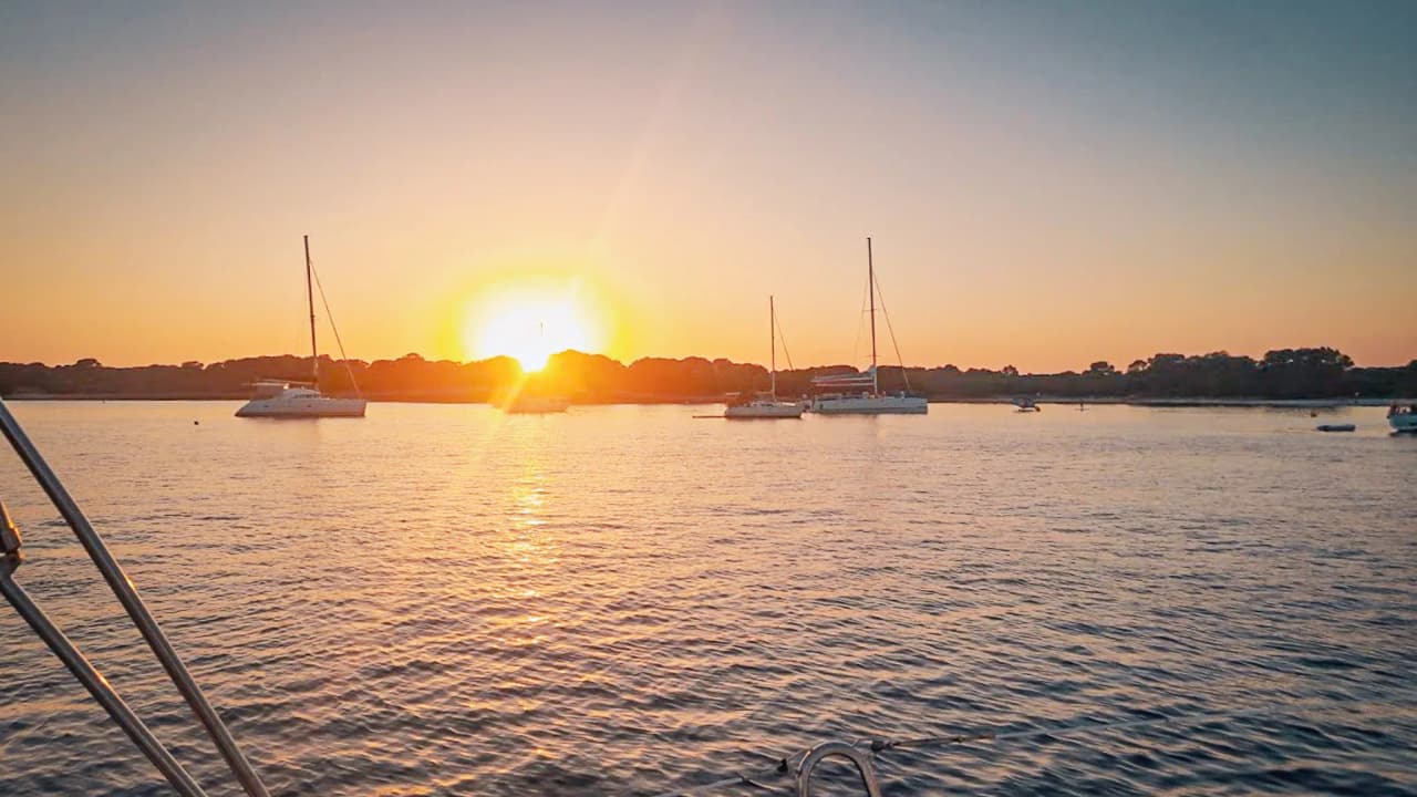 Sunset over the calm waters of the Balearic Islands, sailing boats at anchor – an invitation to travel.