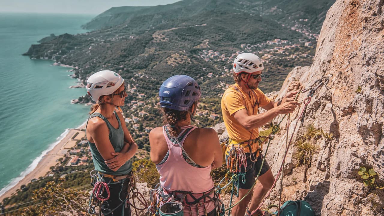 Three climbers at the summit, admiring the Mediterranean and the scenery around Finale Ligure.