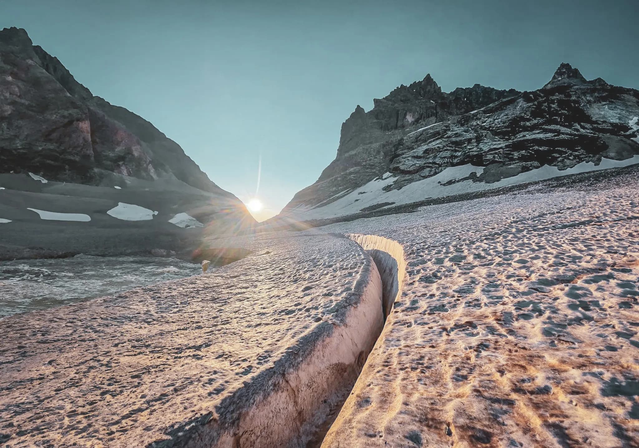 Spectacular view of a glacier under a rising sun, majestic mountains in the background.