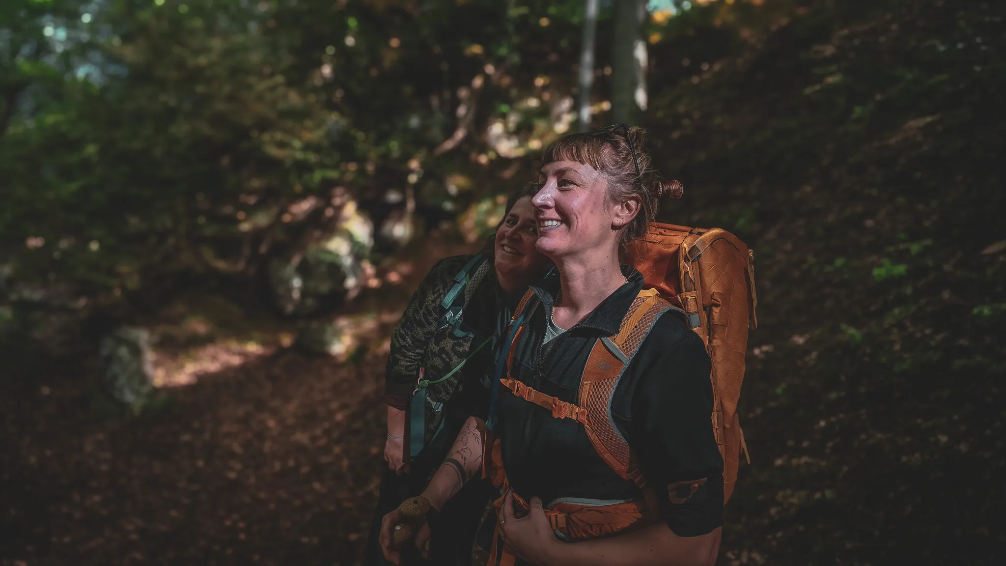 Deux randonneuses souriantes au cœur d'une forêt luxuriante, prêtes à explorer.
