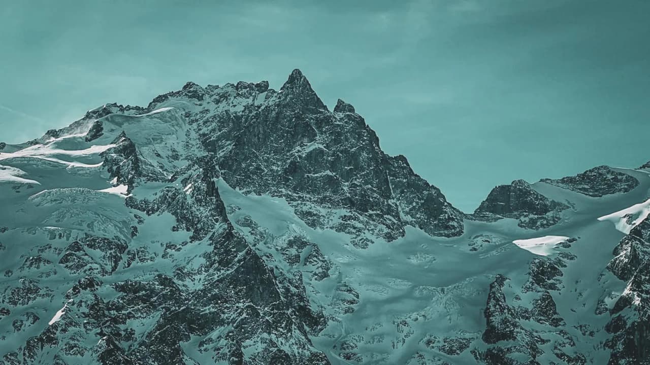 Majestueuze besneeuwde bergen onder een turquoise hemel, een uitnodiging voor avontuur in het hart van de natuur.