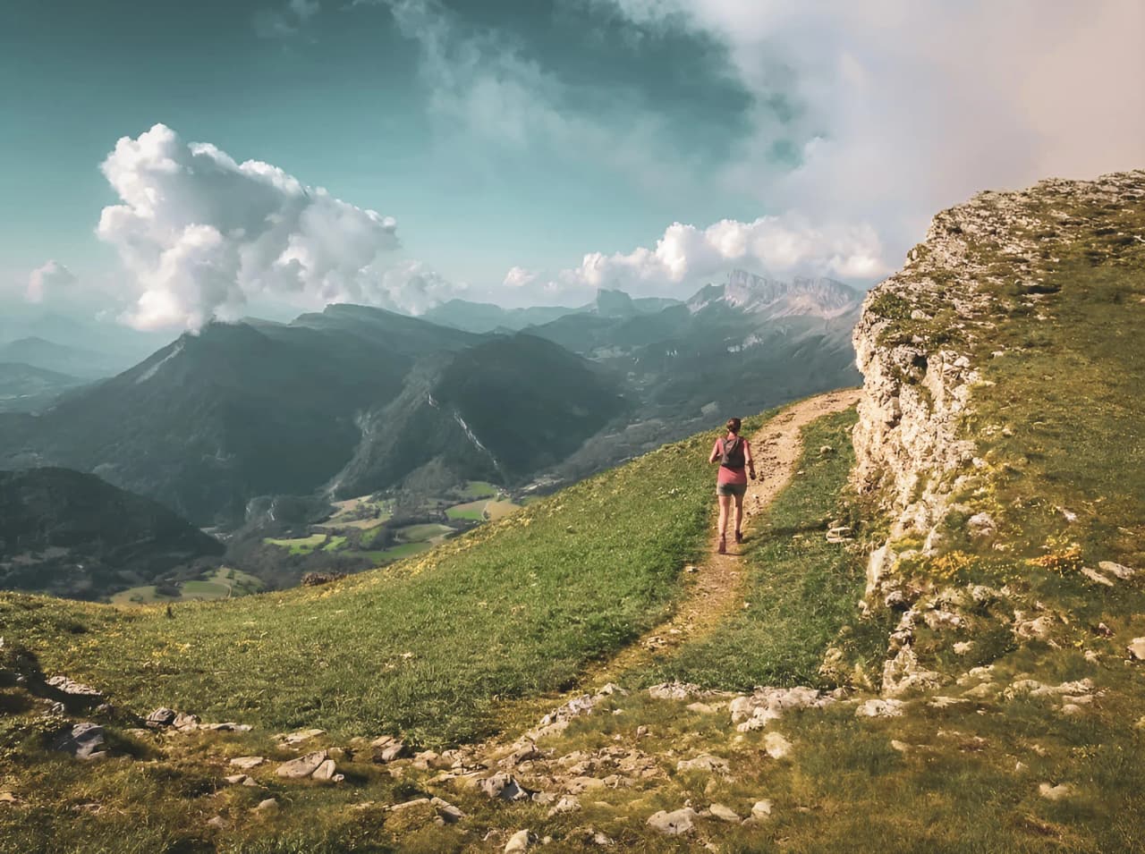 Wandelaar op een groen pad met panoramisch uitzicht op de bergen van de Vercors.