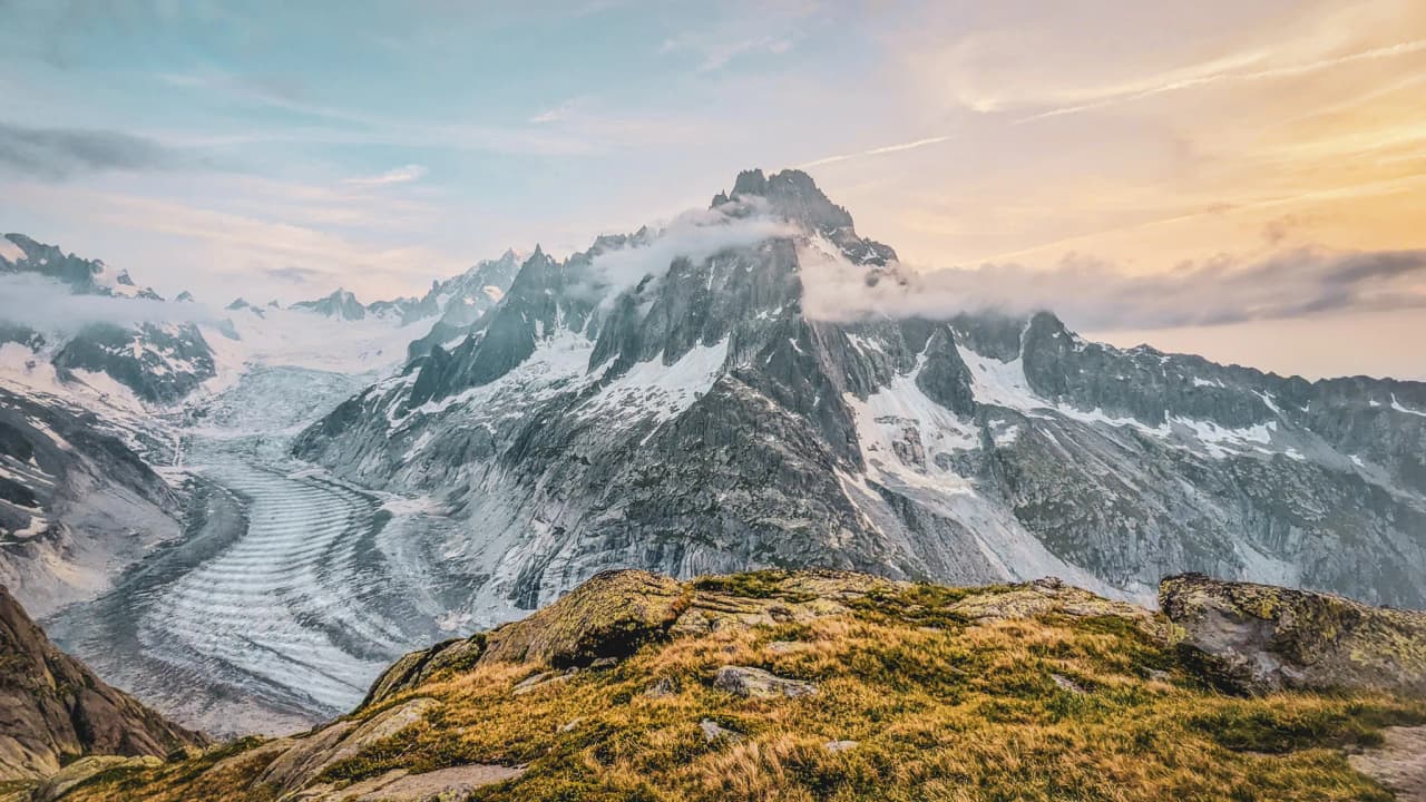 Vue panoramique spectaculaire des montagnes de Chamonix, avec glaciers et ciel pastel.