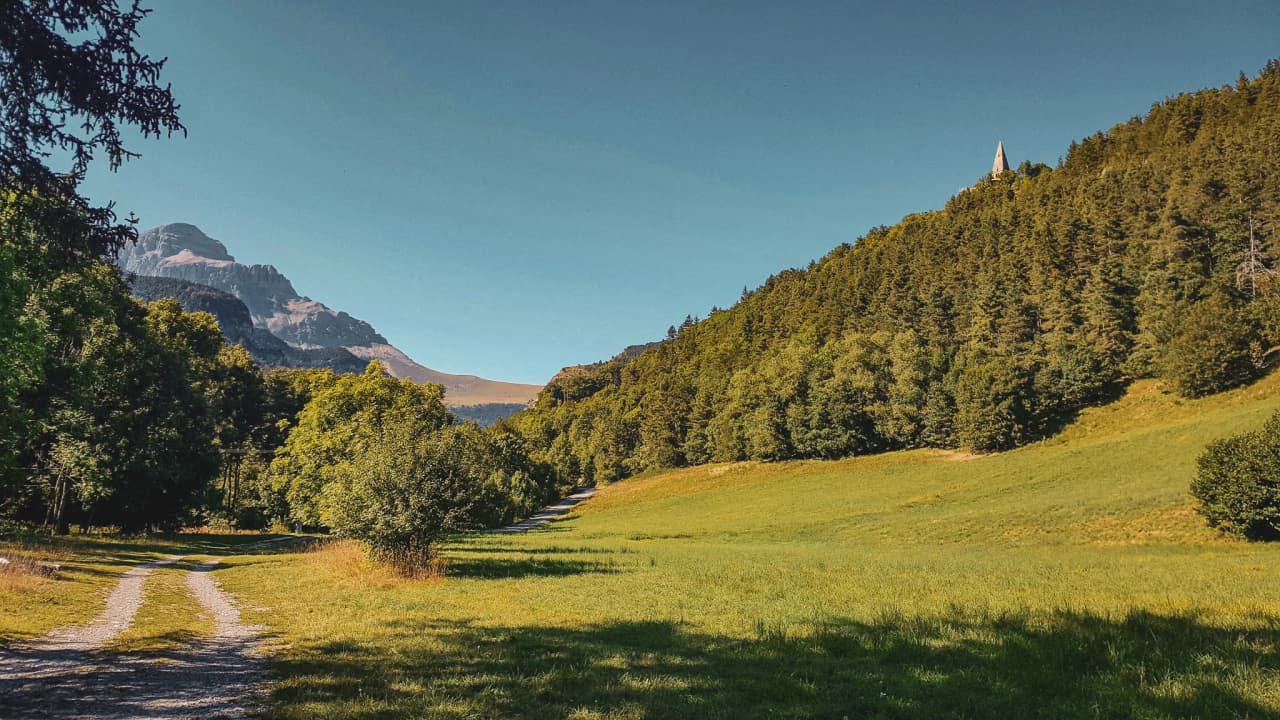 Een kronkelende weg door een groene vallei, omzoomd door majestueuze bergen.