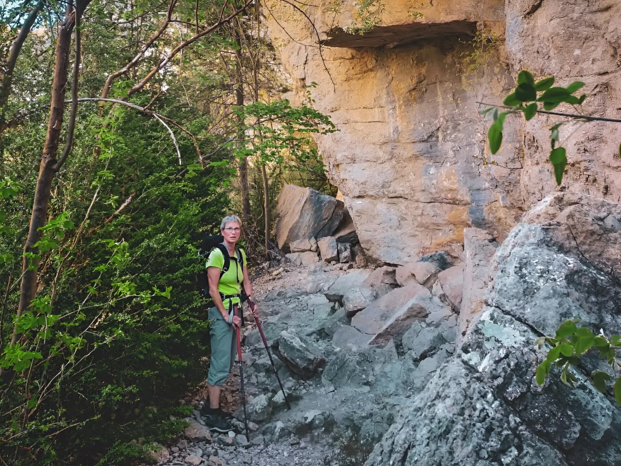 Hiker on a rocky path, surrounded by green forest, in the Vercors High Plateaux.