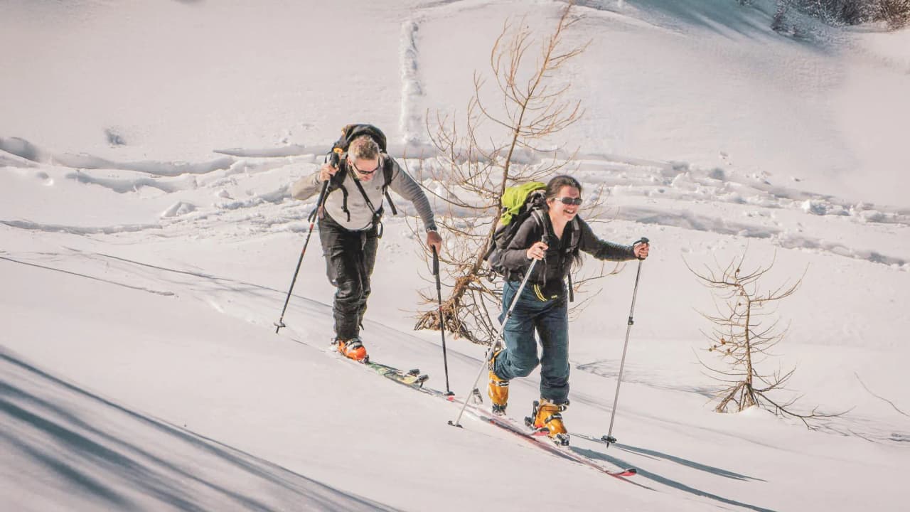 Two skiers happily make their way down the snow-covered slopes of the Italian Alps.