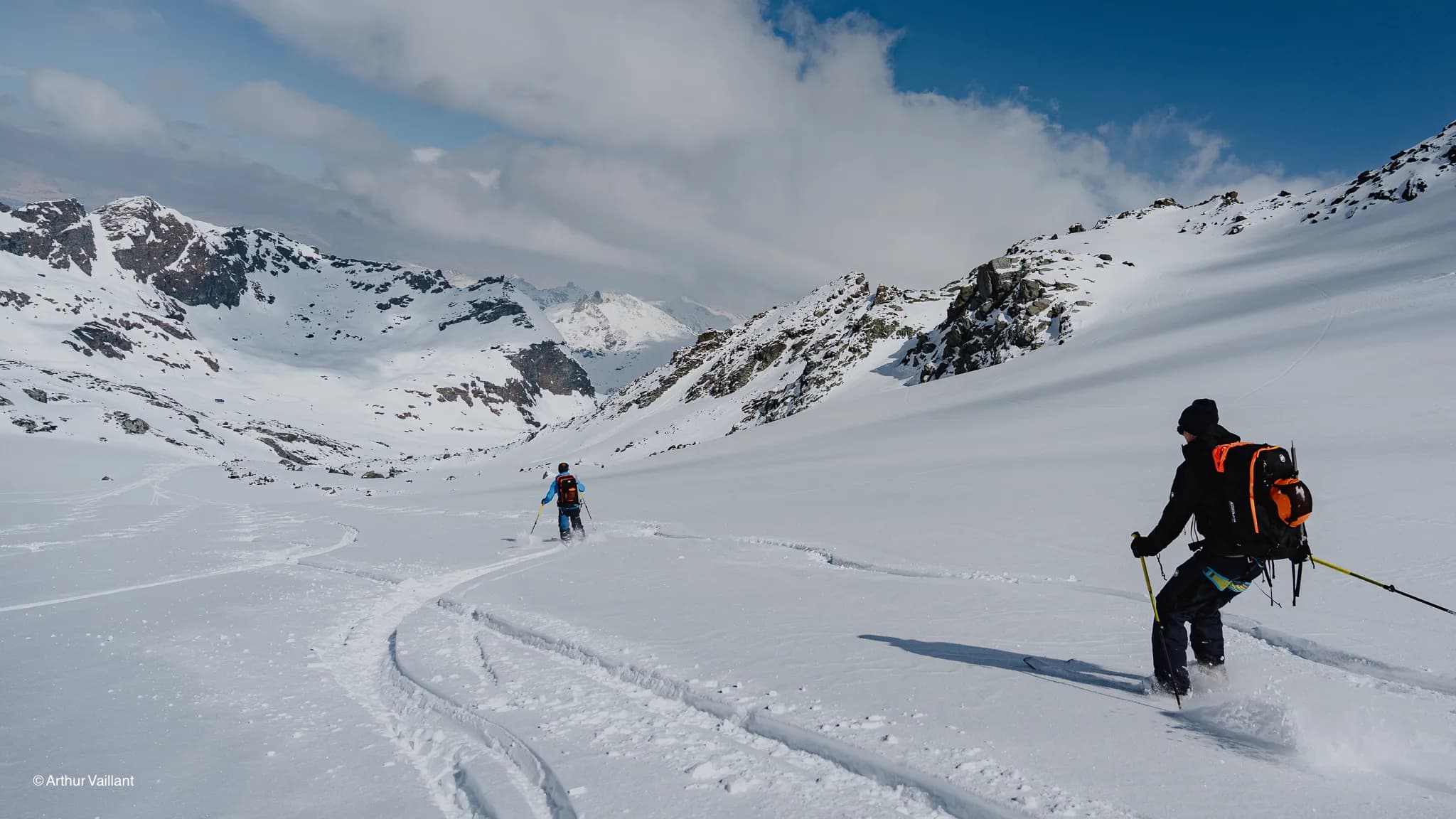 Skiers venturing into a breathtaking alpine landscape, with glistening snow and majestic peaks.