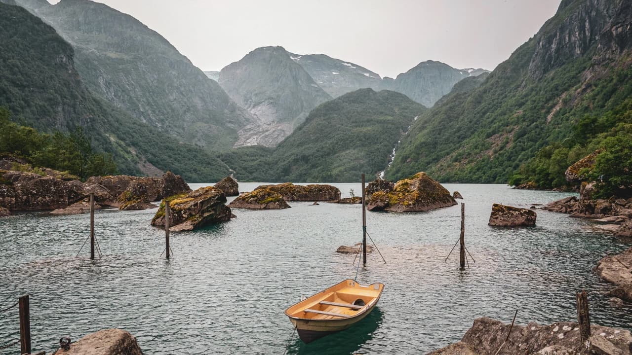 A peaceful fjord in the Lofoten Islands, with green mountains and a small wooden boat.