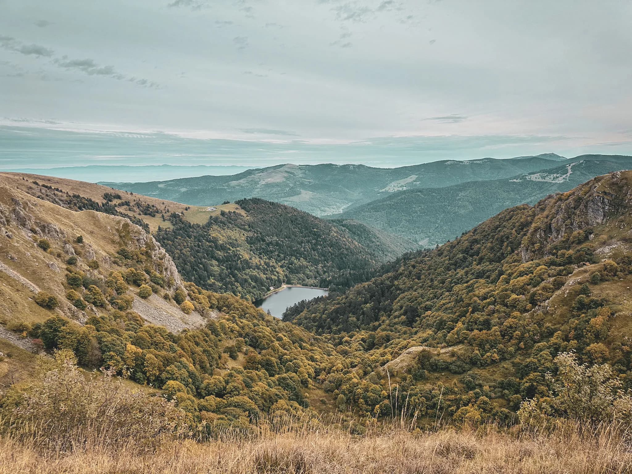 A panoramic view of the Vosges, with green hills and a peaceful lake in the centre.