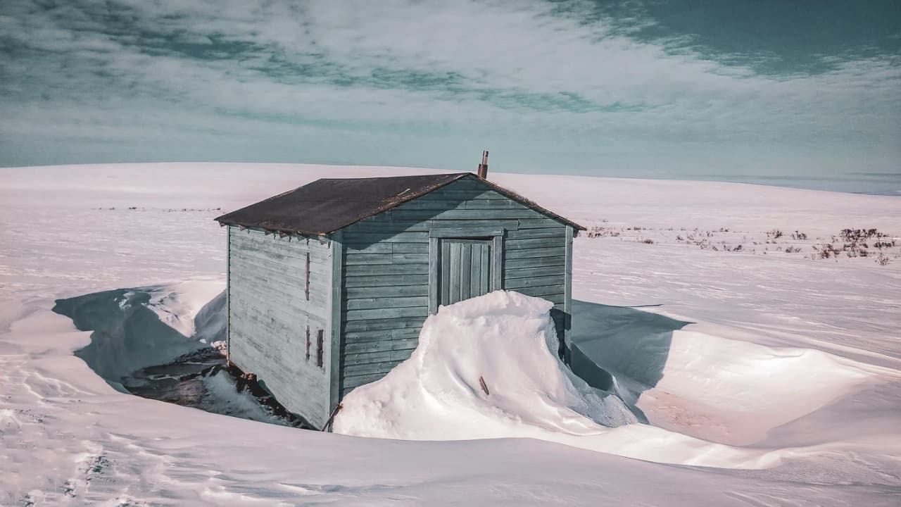 Cabane isolée dans la neige éclatante du Finnmark, invitation à l'aventure en Laponie.