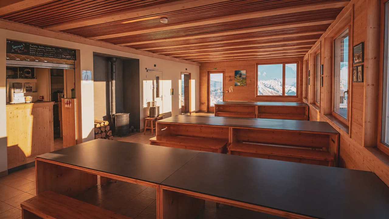 A cosy mountain hut in the Aravis, bathed in light, with views of the snow-capped mountains.