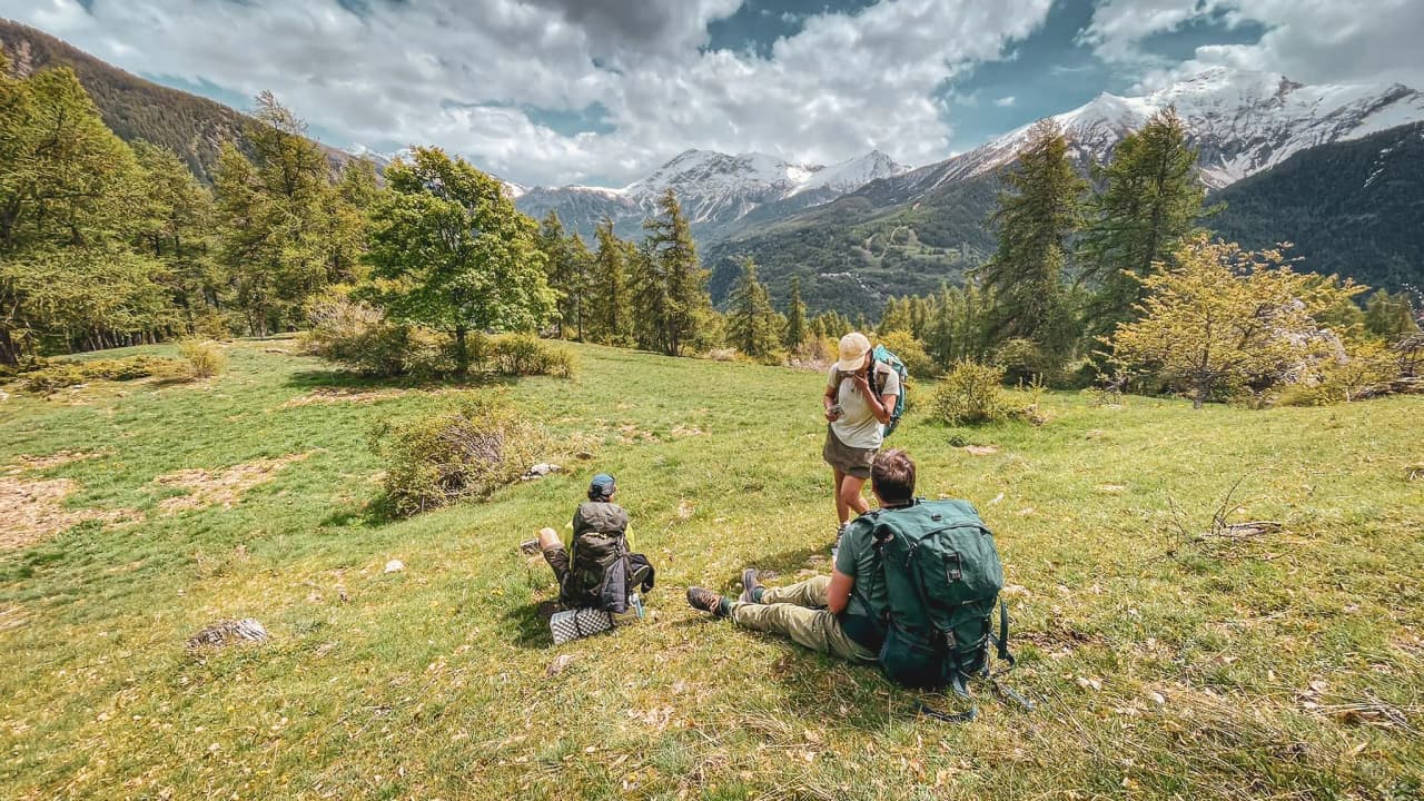 A traveller on a rock, observing the wildlife of the Écrins with binoculars.