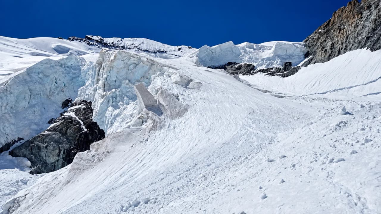Seracs en een gletsjerhelling onder een diepblauwe hemel, op de klimroute.