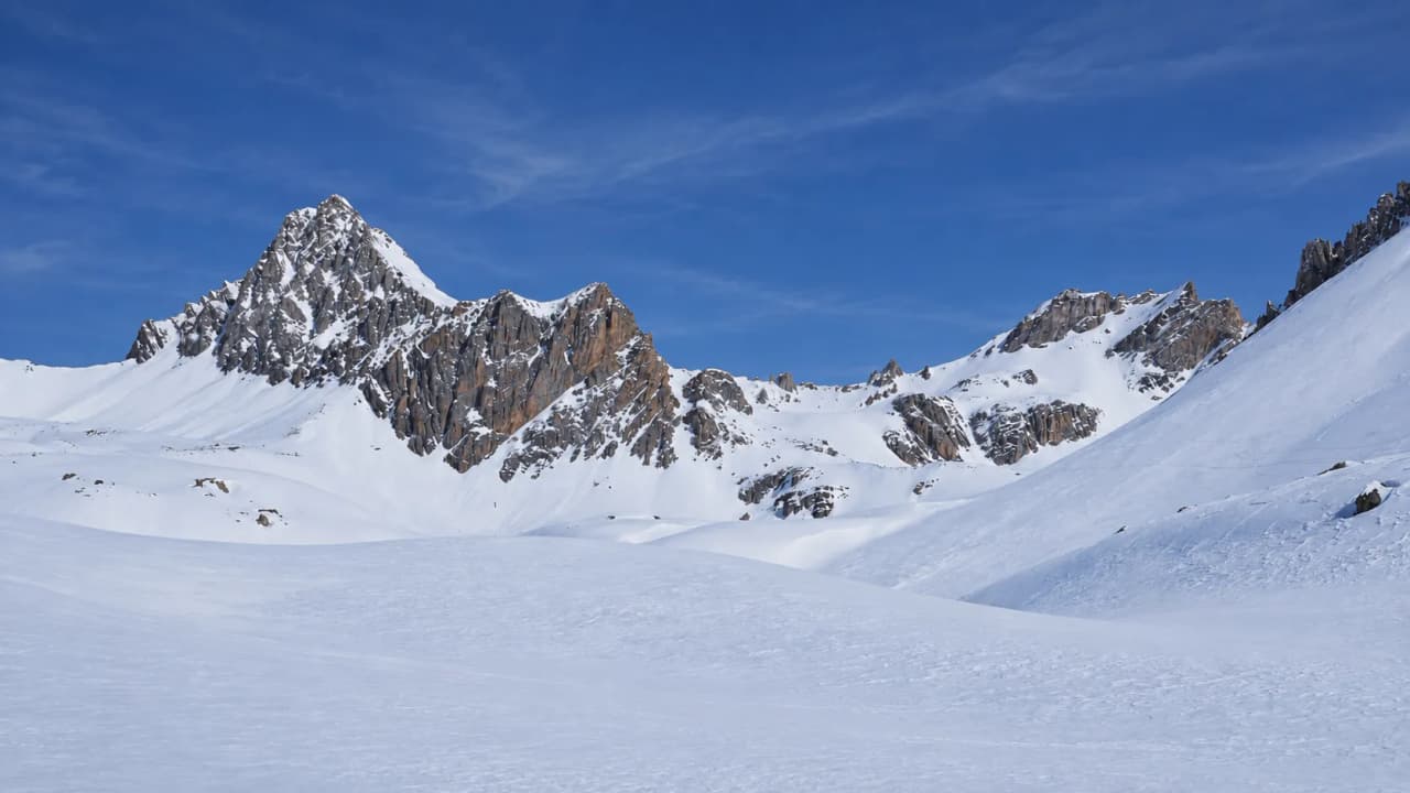 Majestic snow-capped mountains beneath a blue sky – an invitation to a splitboard adventure.
