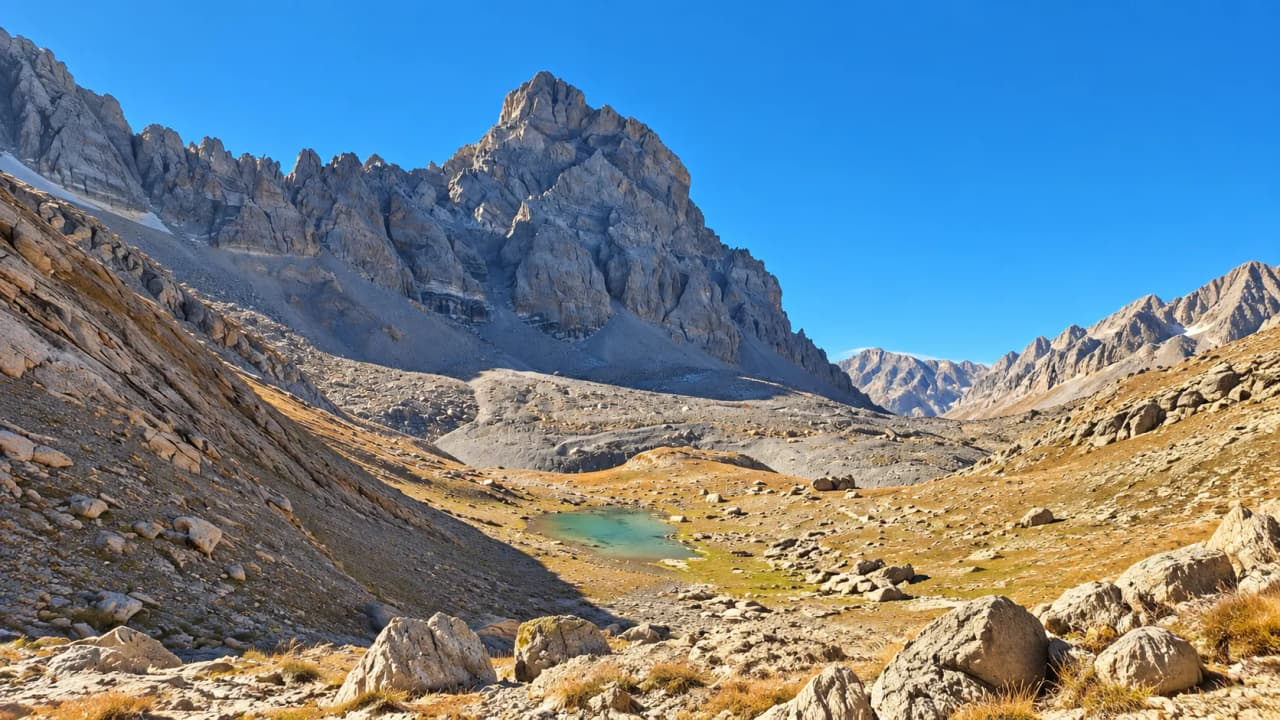 Majestueux paysage alpin avec montagnes escarpées et un lac paisible, invitation à l'aventure.