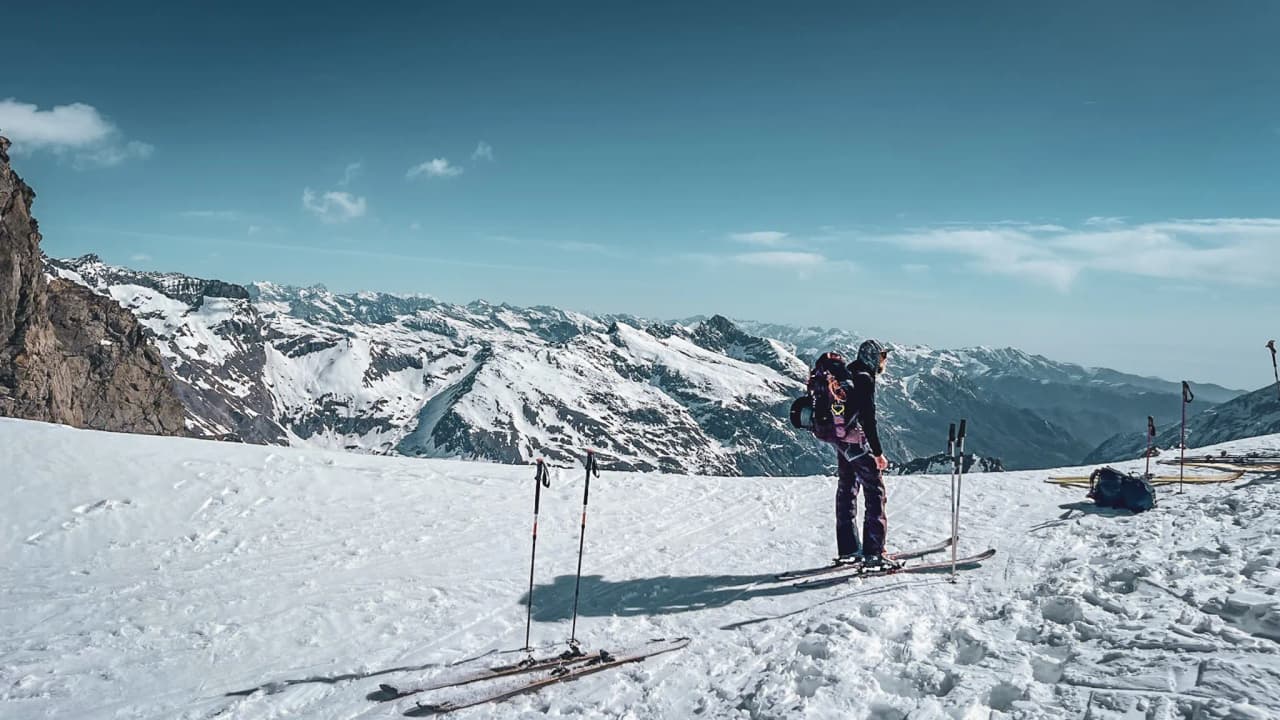 Skier contemplating the Vanoise glaciers, majestic mountains under a brilliant blue sky.