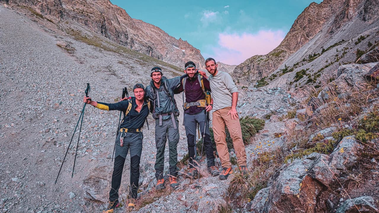 Quatre amis souriants posent en pleine nature, entourés de montagnes majestueuses des Écrins.