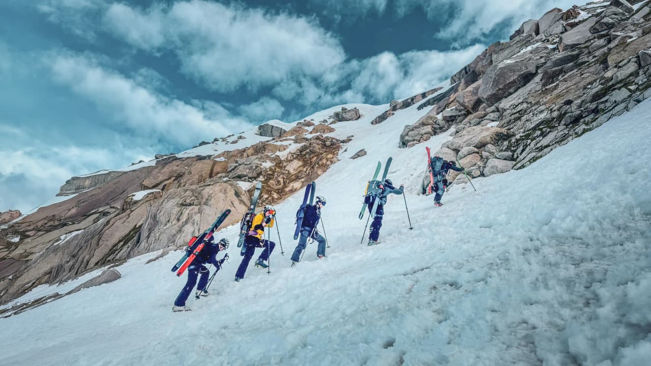 A group of mountaineers climbing a majestic glacier, surrounded by mountains under a blue sky.