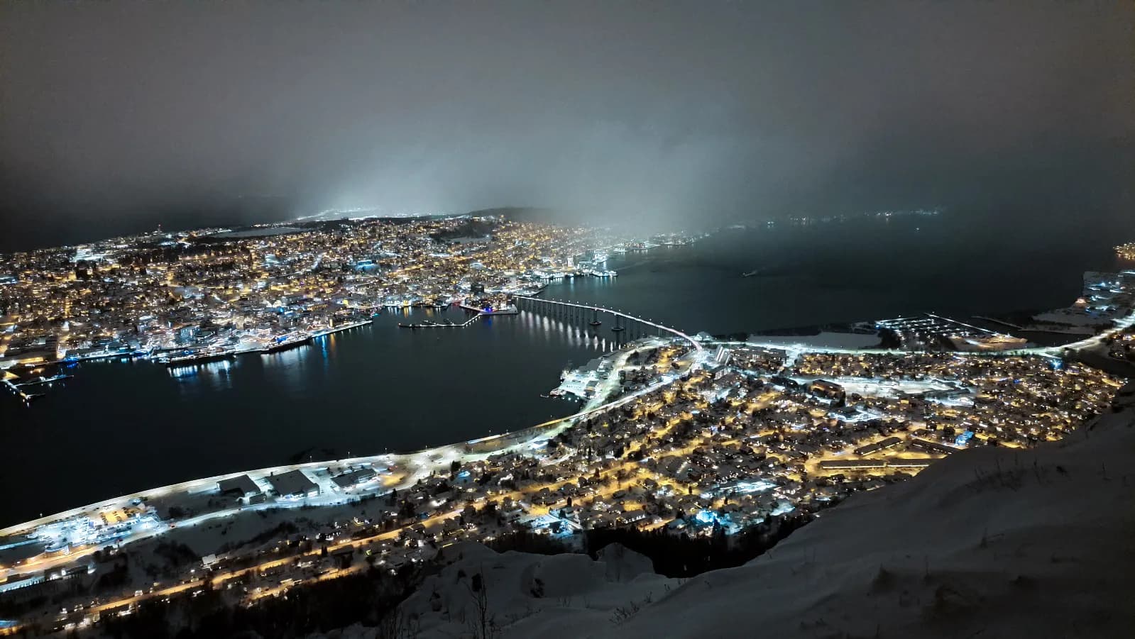 Nachtelijk uitzicht op Senja, glinsterende verlichting over de fjorden onder de sterrenhemel.