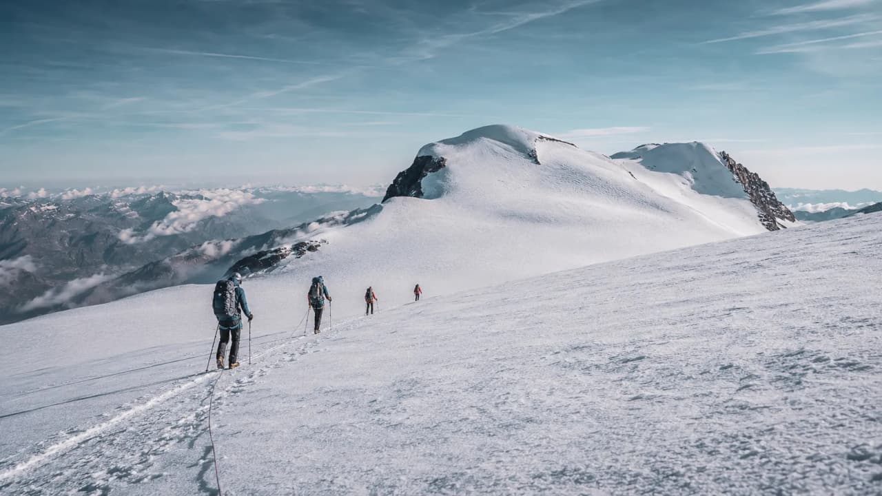 A group of mountaineers climbing the Breithorn Glacier, surrounded by majestic scenery.