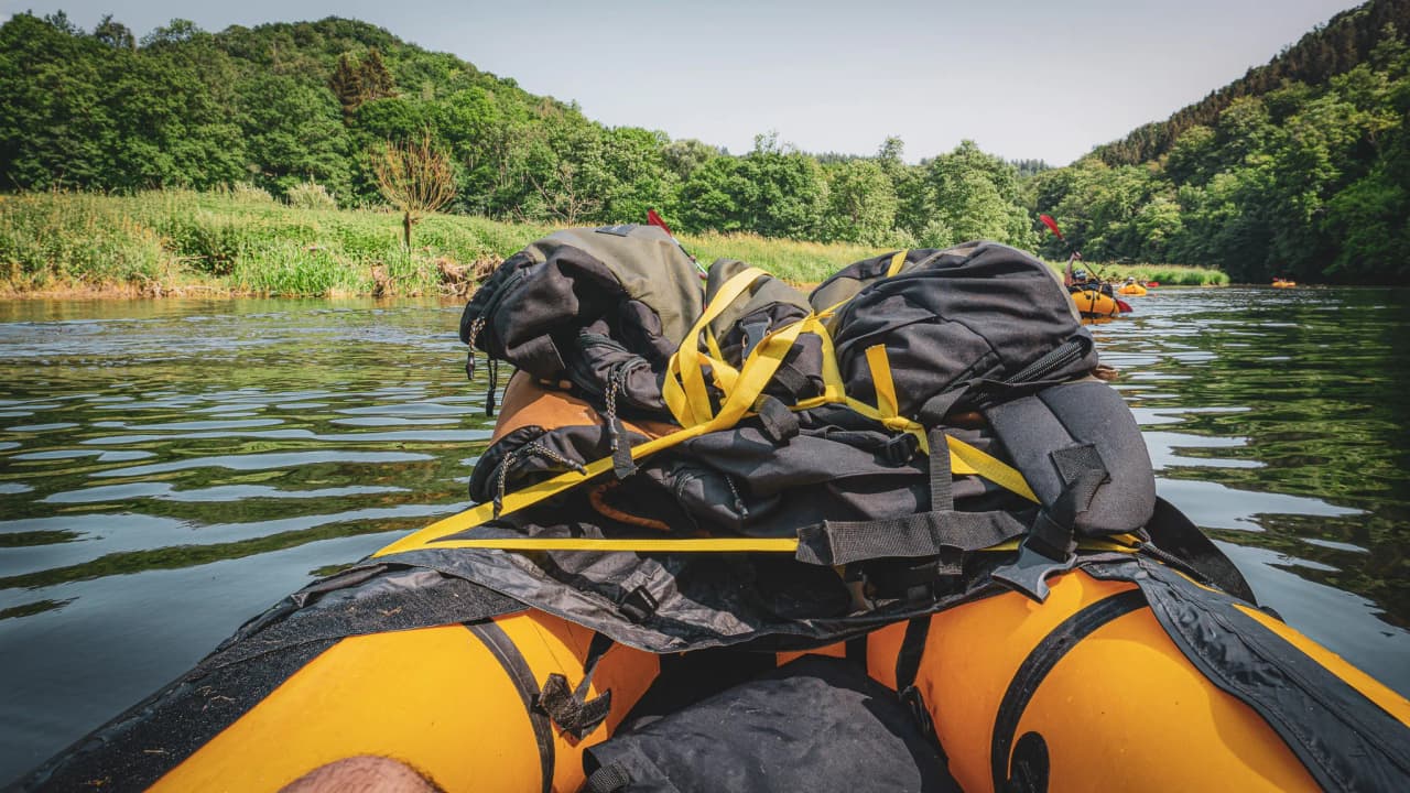 Een rustgevend uitzicht vanaf een packraft op een rivier, omringd door weelderig groen.