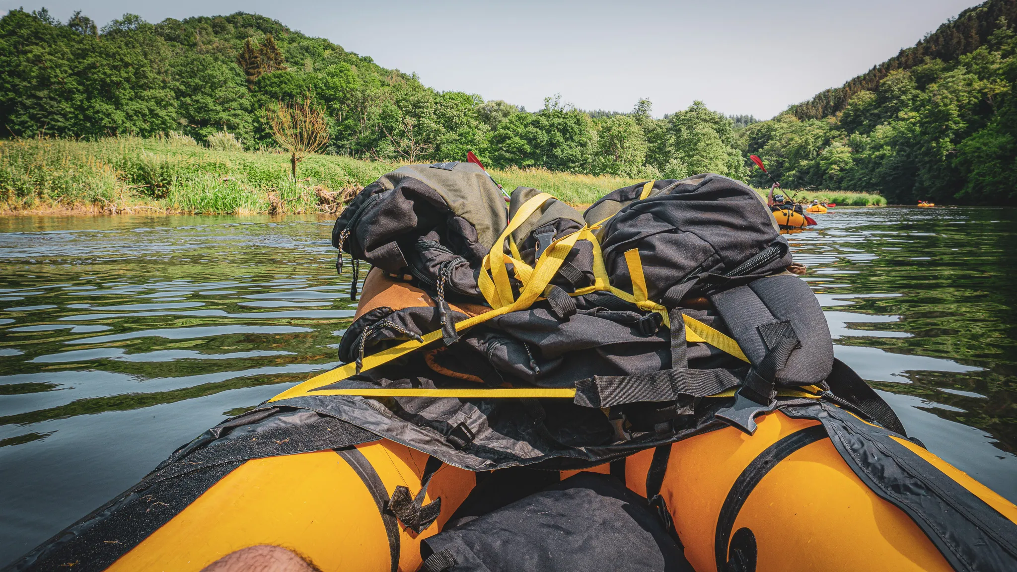 Une vue apaisante depuis un packraft sur une rivière, entourée de verdure luxuriante.