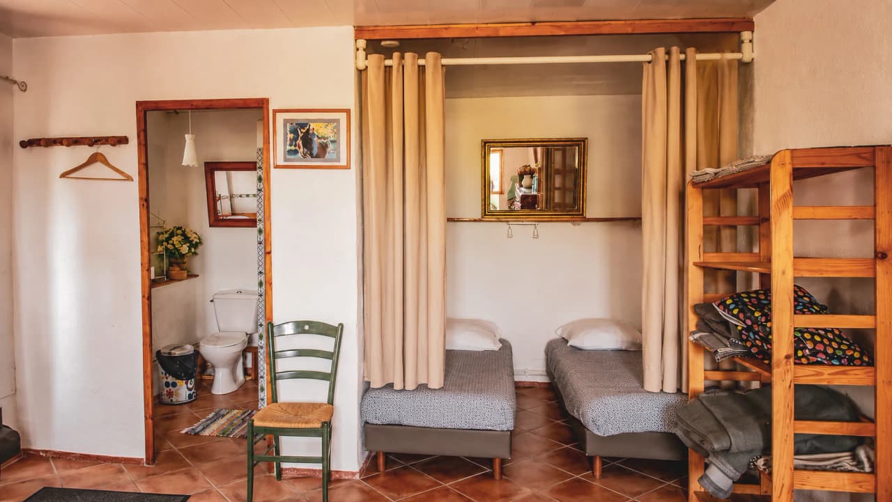 Cosy room with comfortable beds, golden mirror and warm Cévennes atmosphere.