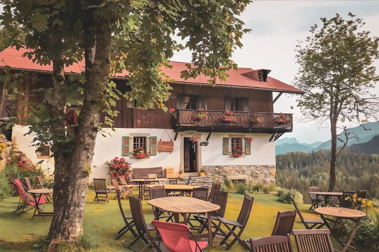 Charming mountain inn with terrace, surrounded by green countryside and mountains.