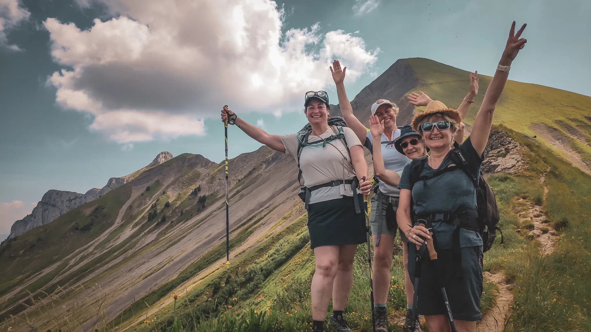 Four smiling hikers on a mountain trail, surrounded by spectacular scenery.