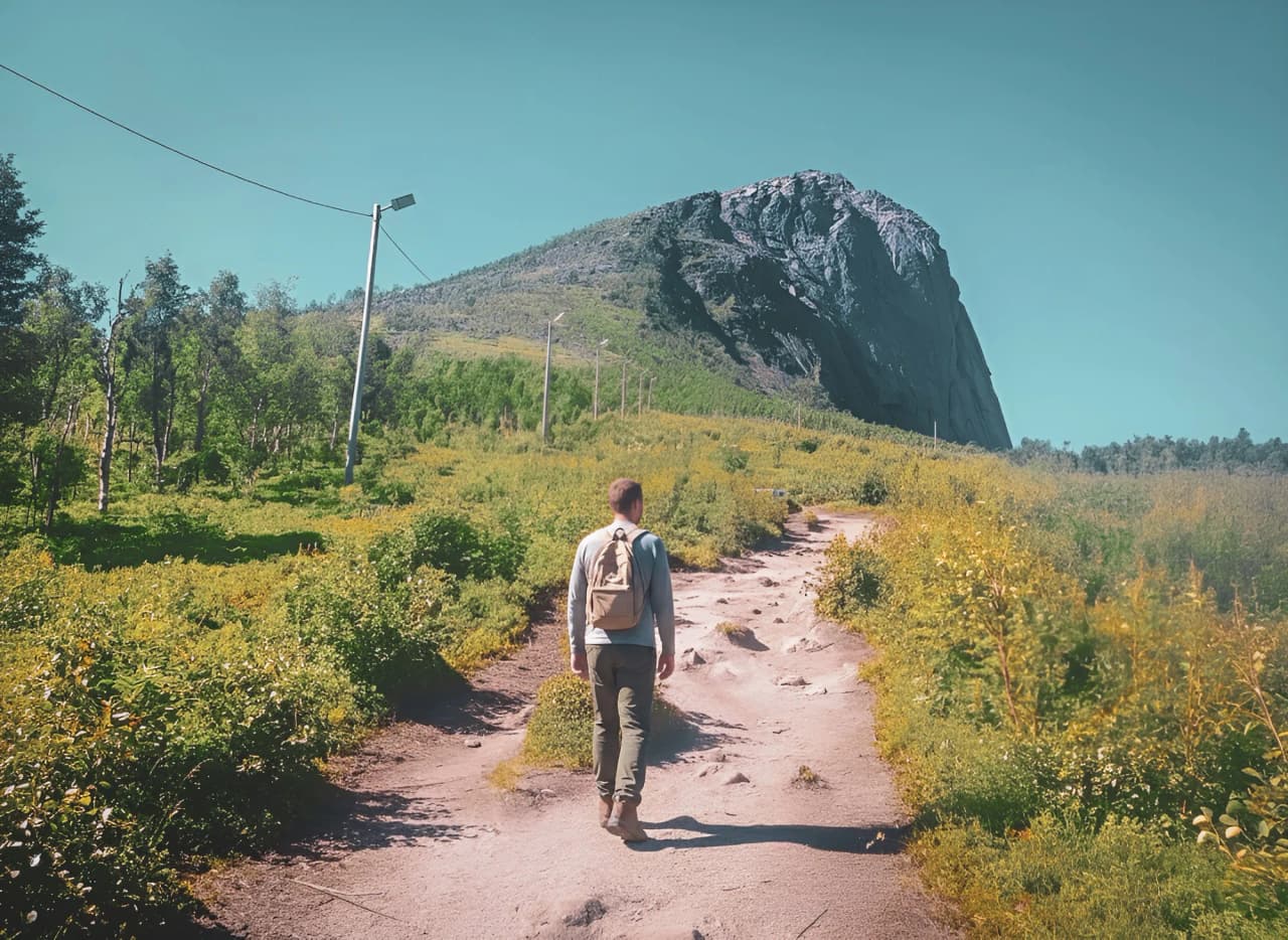 Een wandelaar verkent een groen pad dat leidt naar majestueuze bergtoppen op het eiland Senja.