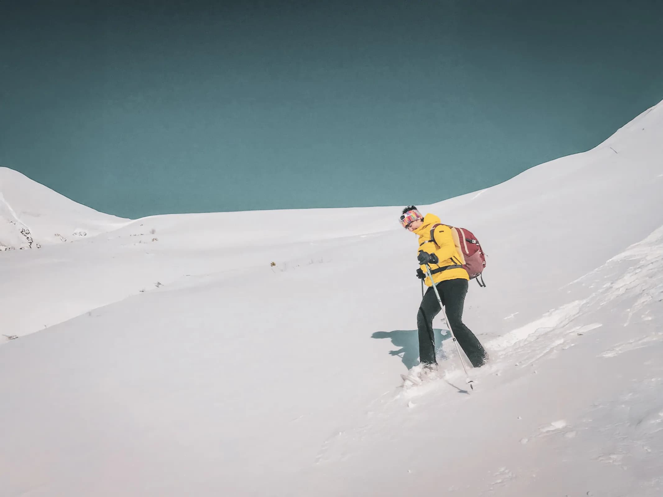 Randonneur en raquettes, vêtue de jaune, explore un paysage enneigé face aux glaciers majestueux.