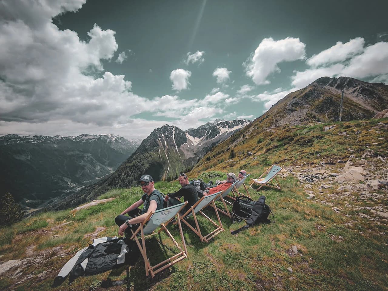 Four friends relax on deckchairs, surrounded by majestic Alpine peaks.
