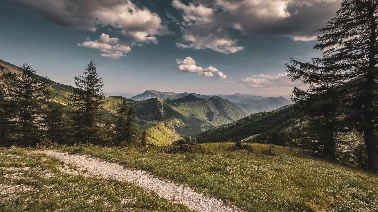 Een majestueus panorama van de bergen van Dévoluy, met kronkelende paden en pluizige wolken.