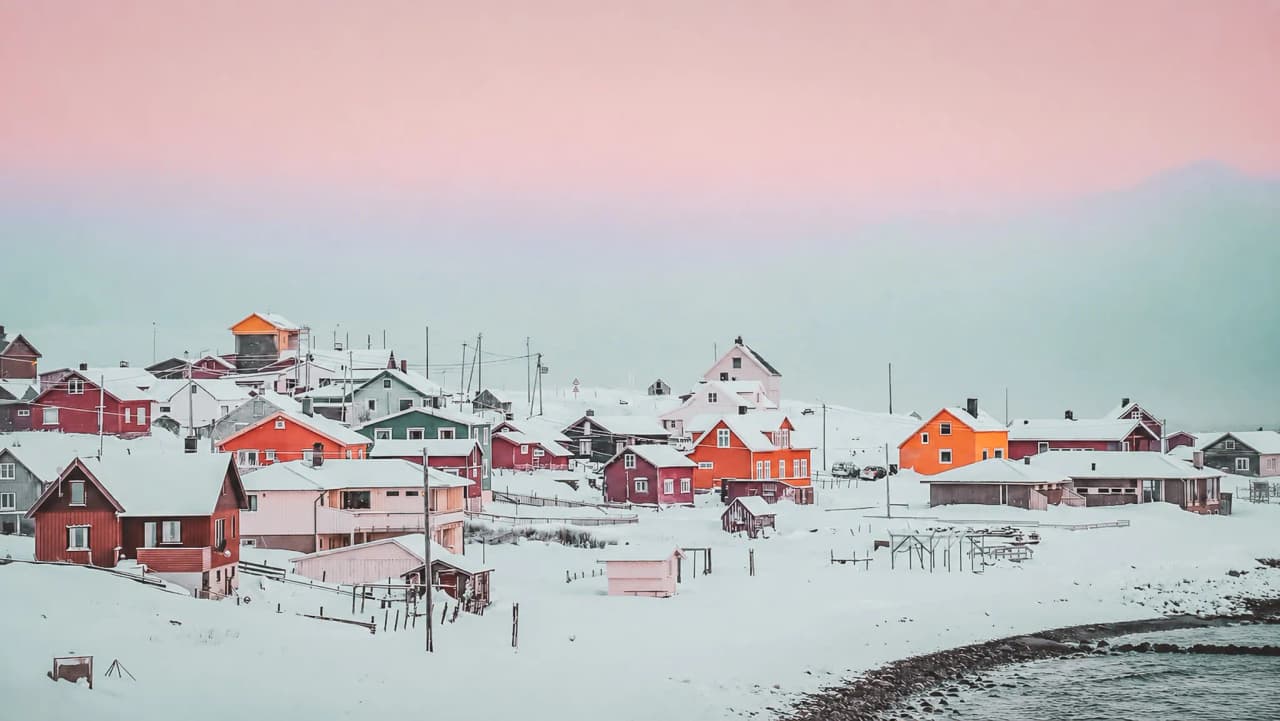 Village coloré sous la neige, entouré de paysages enneigés, évoquant l'aventure en Laponie.