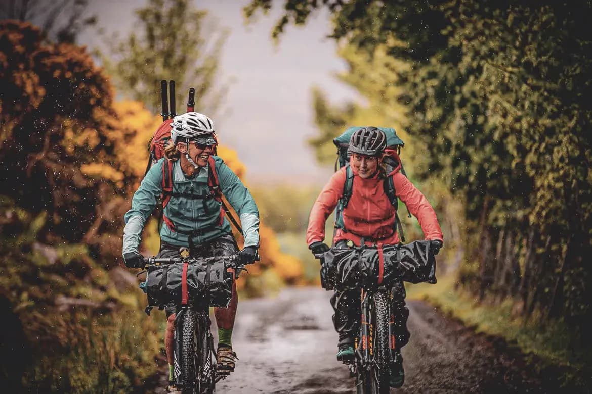 Two smiling cyclists on a country lane, surrounded by nature, ready for adventure.