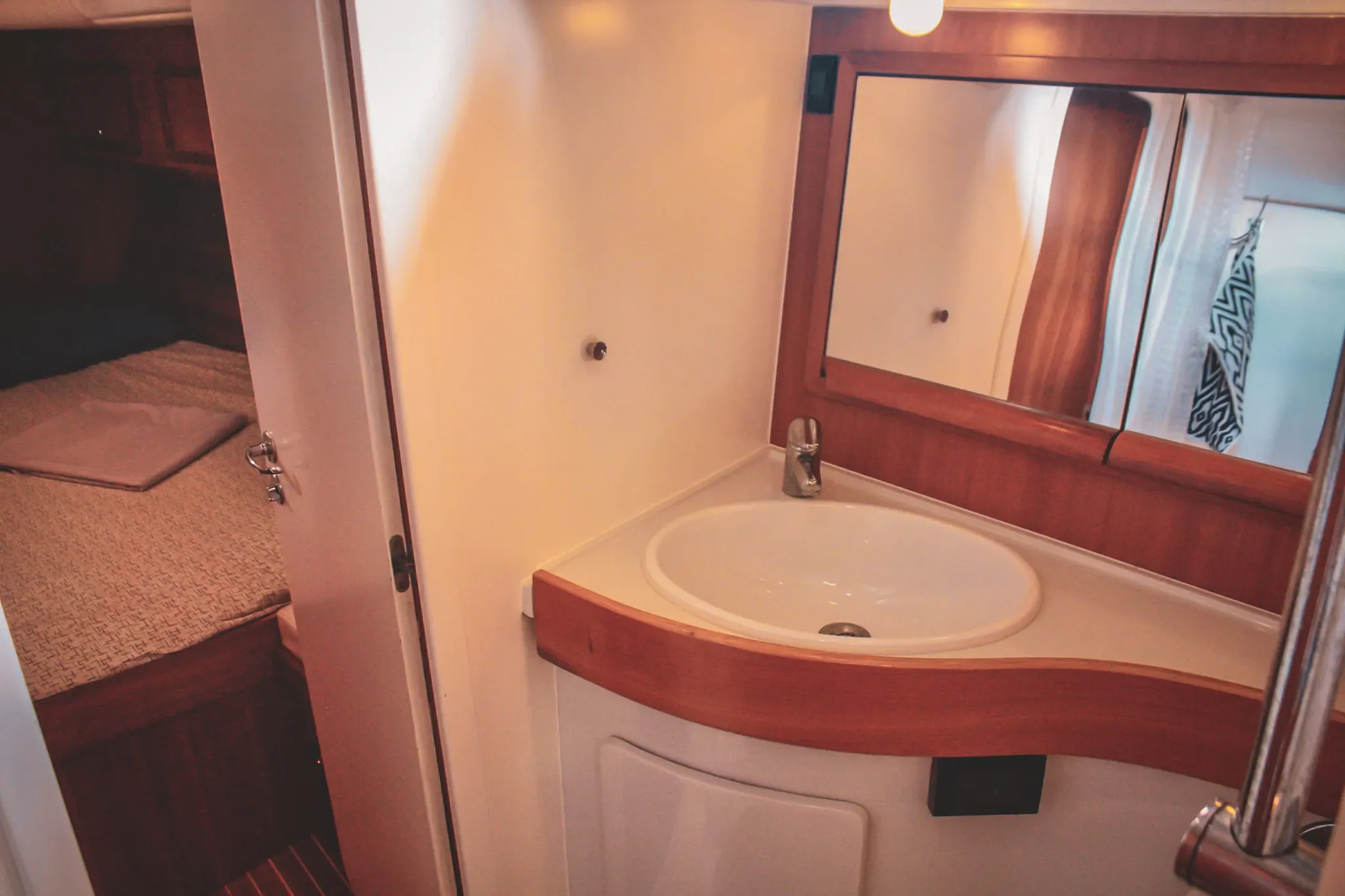 Intérieur d'un voilier, avec lavabo moderne et lit cosy à l'arrière, invitant à l'aventure maritime.
