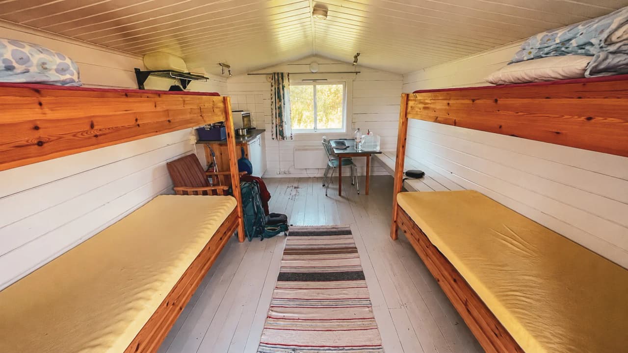 Intérieur d'un refuge en Laponie, avec lits confortables et lumière naturelle, parfait pour se reposer.