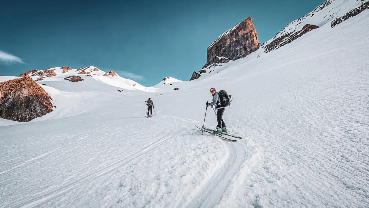 Ski de randonnée sur un vaste glacier, montagnes majestueuses en toile de fond. Aventure alpine à couper le souffle.