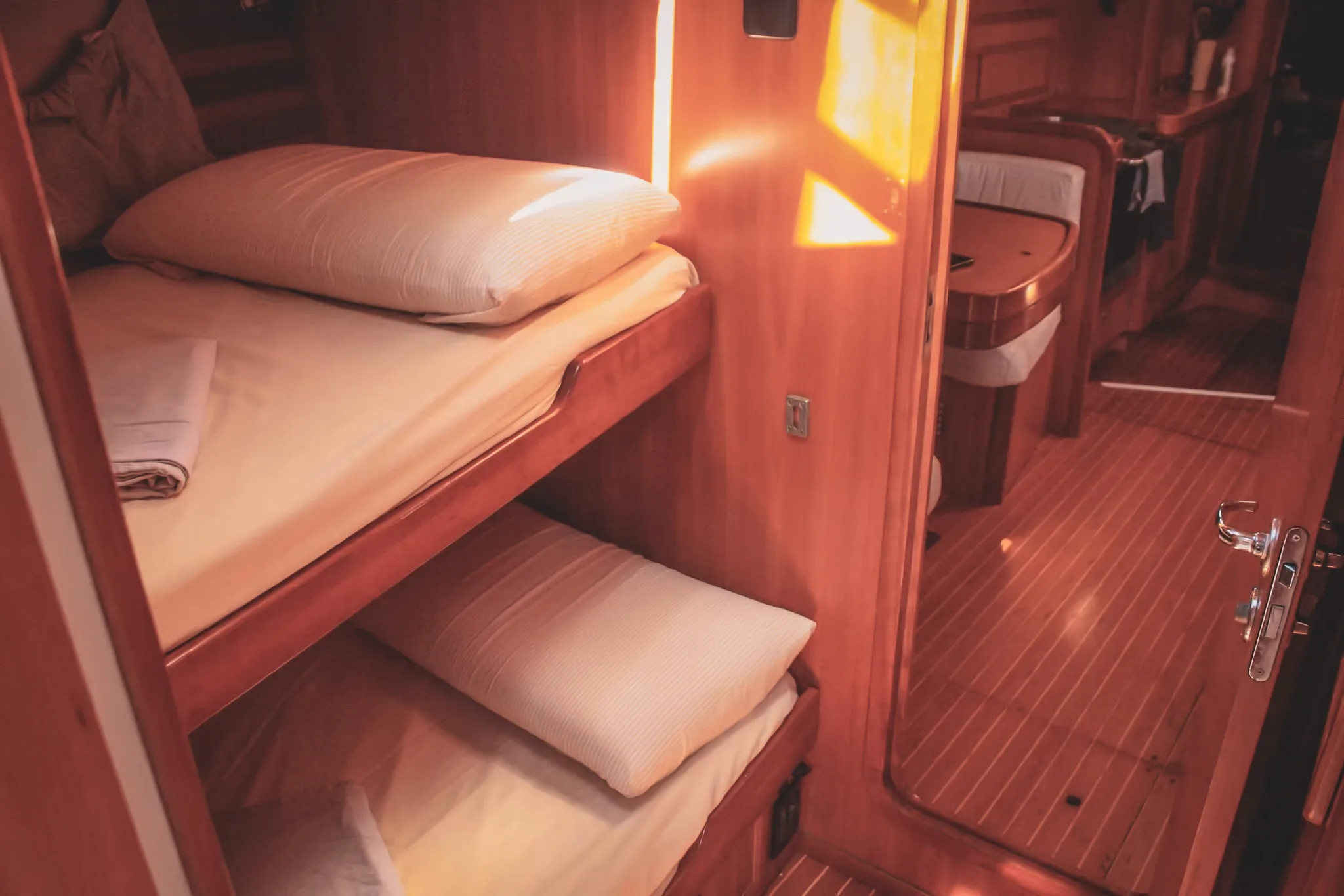 Cabine chaleureuse d'un voilier, avec lits confortables et bois poli, parfaite pour des escapades en mer.